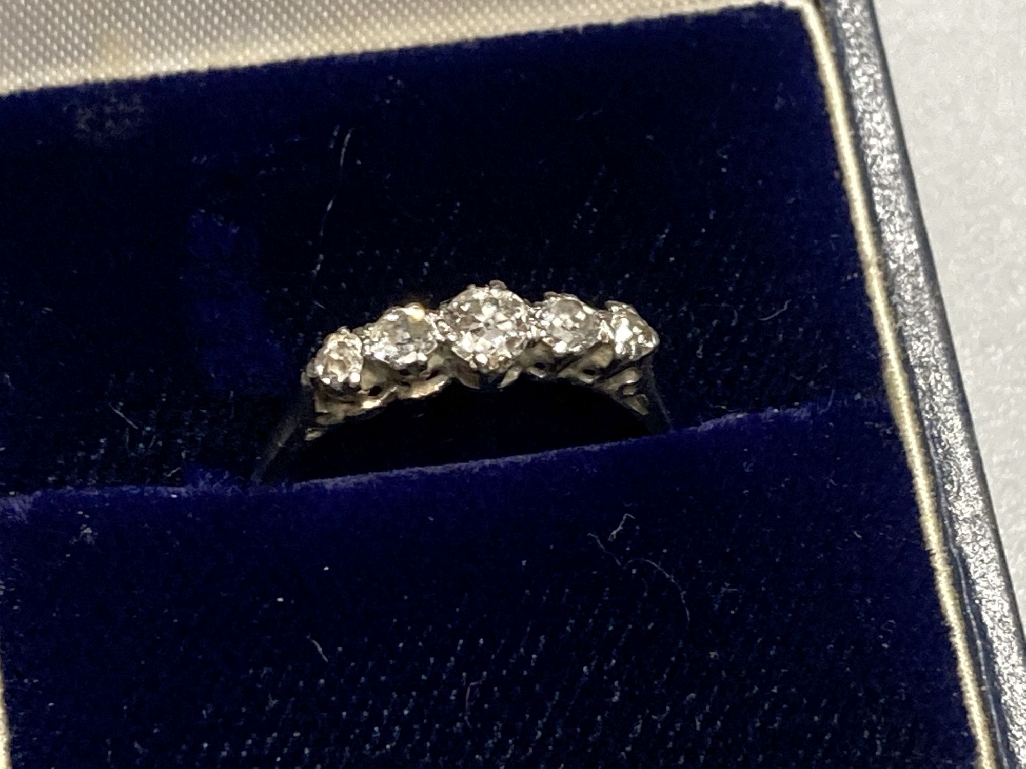 A 1940s/1950s white metal (stamped platinum) and graduated five stone diamond set half hoop ring, size K/L, gross 2.4 grams.